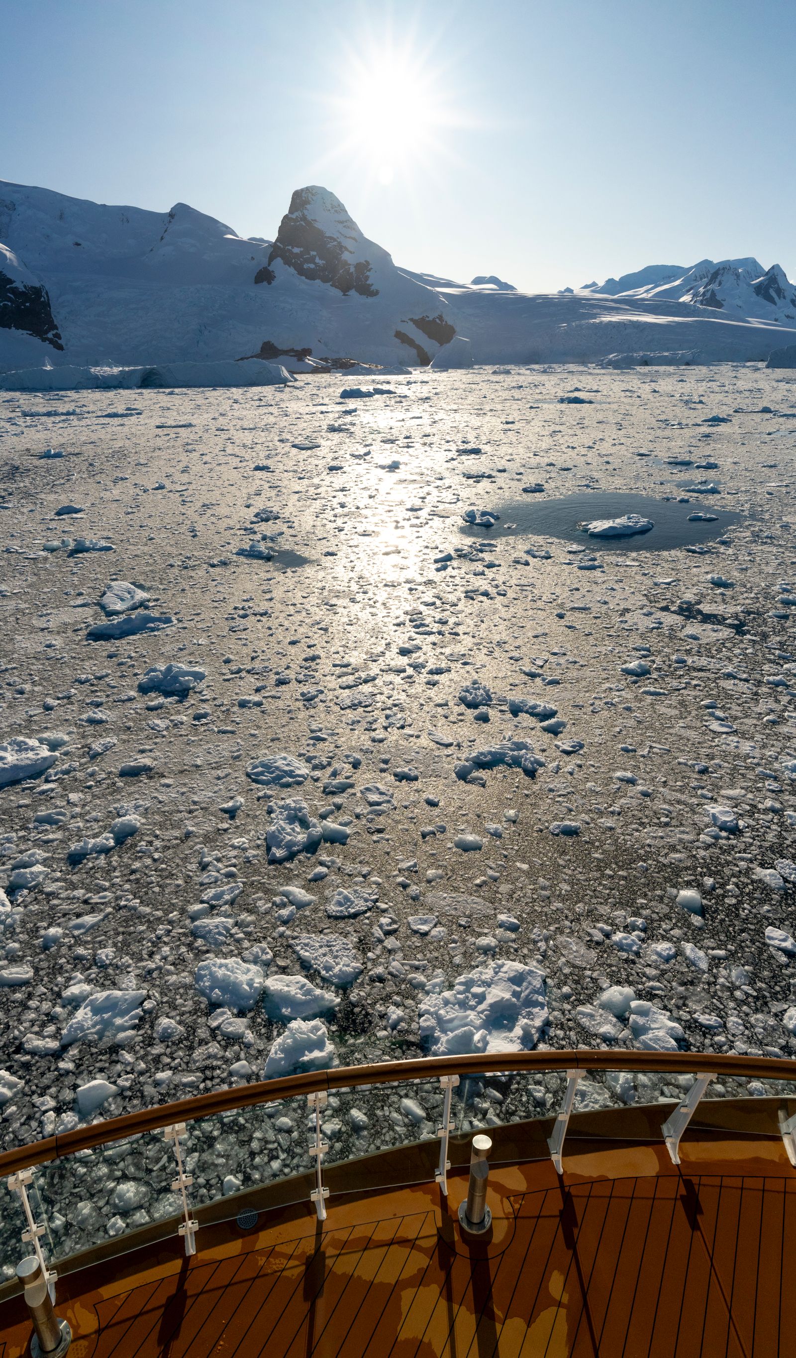 View of brash ice and mountains from the deck of a small expedition ship in Antarctica
