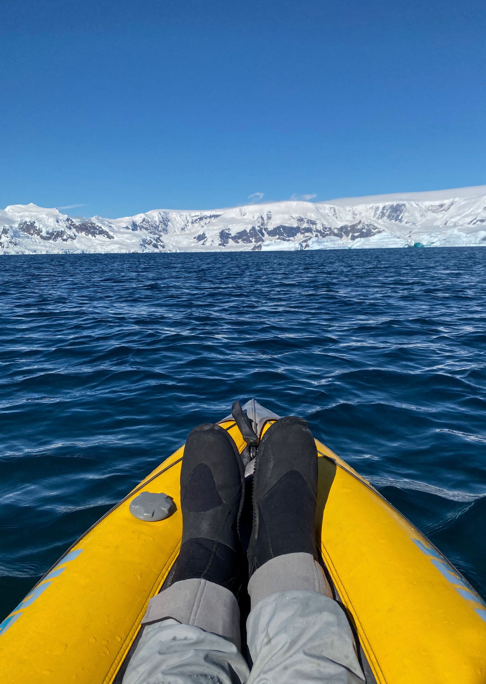 Sea kayaking on calm water along the Antarctic Peninsula with mountains in the distance